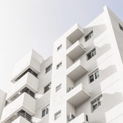 Low angle shot of a facade of a white modern building under a blue clear sky A low angle shot of a facade of a white modern building under a blue clear sky